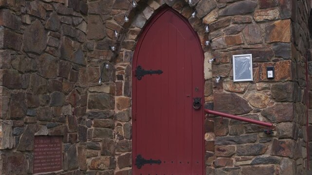Red arched wooden door on a historic stone building