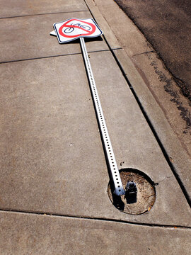 Broken and Fallen No Biking Sign on Sidewalk Snapped and Laying on Ground