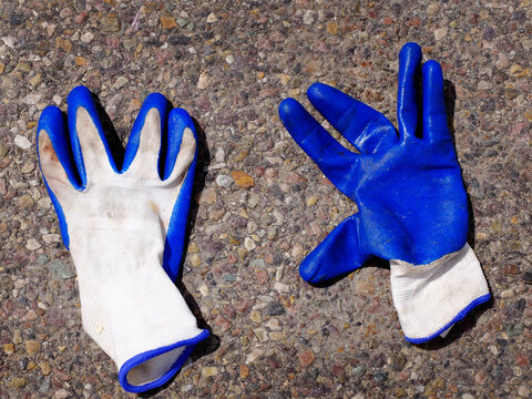 Old Abandoned Rubber Work Gloves Blue and  White Laying on Asphalt Road Roadway
