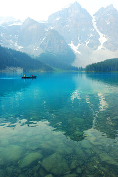 Several Groups of People in Red Canoes Floating on Brilliant Blue Lake in the Wilderness Mountains Enjoying Nature Outdoors