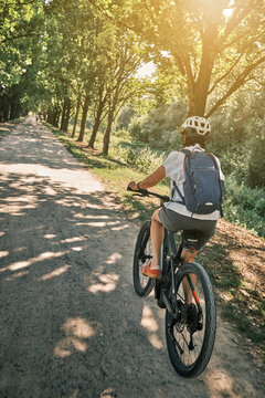 Active woman cycling on a sunny Sunday afternoon along a historic tree-lined avenue in Monrepos Park. Ludwigsburg, Baden-W&uuml;rttemberg, Germany.