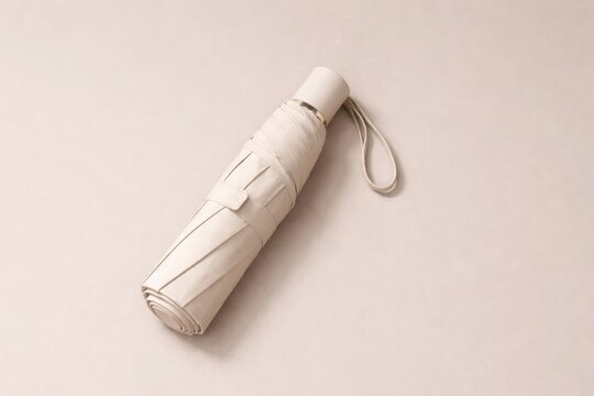 Minimalist folded white umbrella isolated on soft beige background with elegant clean product presentation