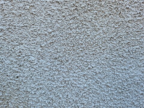 White rough stucco concrete wall texture background with granular popcorn plaster surface