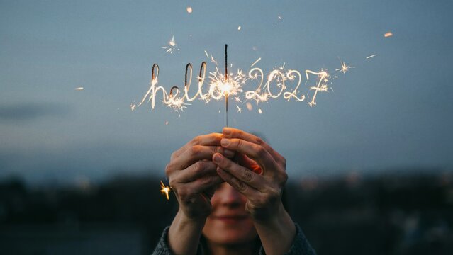 A close up of a person holding a burning sparkler in their hands during a beautiful twilight evening