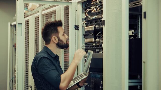 IT Engineer Holding Laptop Checking Cables In Server. Rack Data Center Maintenance. Hardware Diagnostics