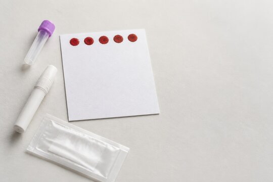 Newborn screening card with dried blood spots, sterile lancet and collection materials arranged on a clean clinical surface
