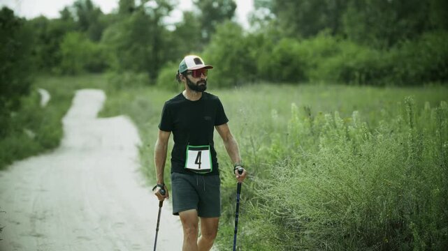Athlete Participating In Nordic Walking Race Competition. Hiking With Trekking Poles On Dirt Path 