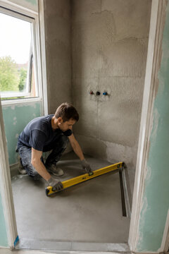 Trabajo en la construcci&oacute;n de un ba&ntilde;o mientras se nivela el suelo con un nivel