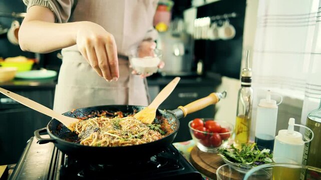 Cook Adding Salt Seasoning To Pasta In Frying Pan. Cooking Italian Meal In Kitchen