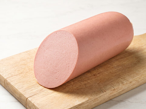 Cut piece of bologna sausage resting on a wooden cutting board