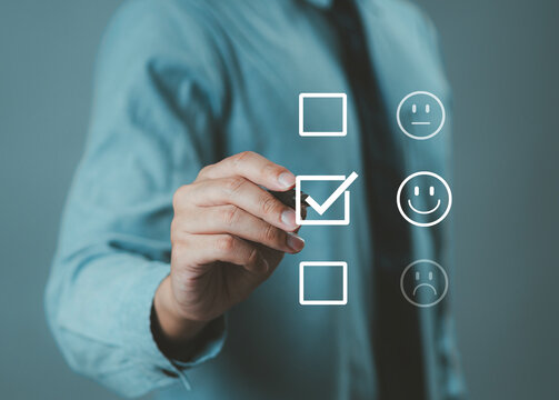 The hand is giving a five-star rating. The business person selects the smiley face icon on the virtual screen to express their satisfaction with the service. The rating received is very impressive.