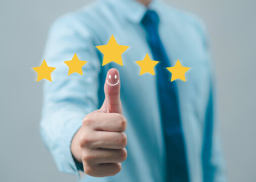 The hand is giving a five-star rating. The business person selects the smiley face icon on the virtual screen to express their satisfaction with the service. The rating received is very impressive.