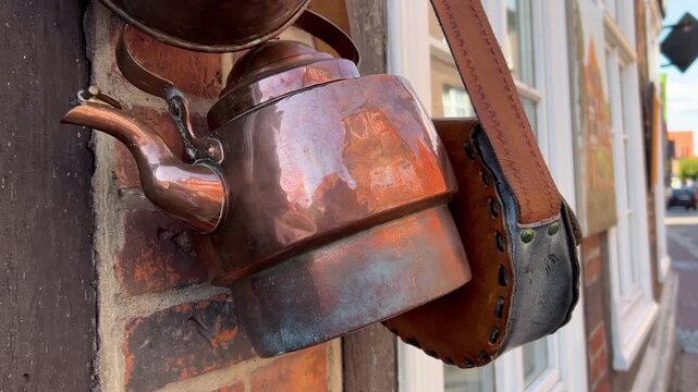 Close-Up of Old Weathered Metal Kettle Hanging with Vintage Cookware on Exterior Wall