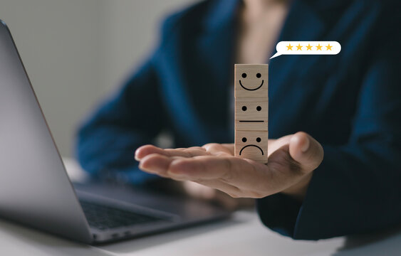 The concept of customer rating and satisfaction: Customers' hands select feedback using wooden smiley face cubes to indicate their satisfaction with the service.