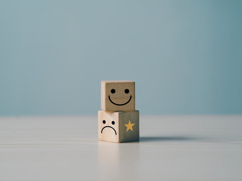 The concept of customer rating and satisfaction: Customers' hands select feedback using wooden smiley face cubes to indicate their satisfaction with the service.