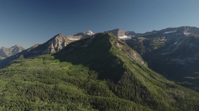 An aerial shot of a forest and  the north side of Mount Timpanogos in the afternoon in Summer, Utah, USA