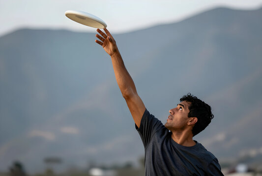 Young man reaching for a frisbee in mid-air during outdoor recreational activity, fitness and leisure concept, a young man reaches upward with his arm extended