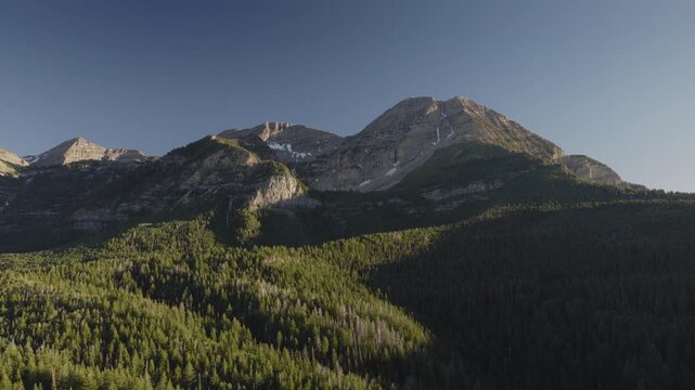 An aerial shot of a forest and  the north side of Mount Timpanogos in the afternoon in Summer, Utah, USA