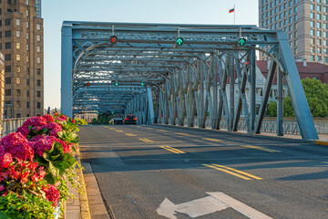 Historic Waibaidu steel truss bridge with traffic road surrounded by historic urban architecture in Shanghai city, China. Transportation infrastructure, industrial design, city mobility