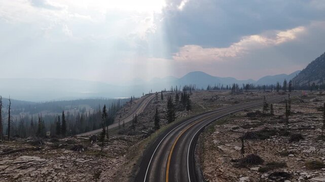 Aerial of mountain pass highway 150 through Uinta Wasatch Cache National Forest traversing an arid plateau with distant Uinta mountains in Utah with dramatic sky
