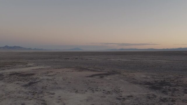 An Aerial shot of an vast desert and distant mountains at dusk near Sevier Lake, Utah, USA