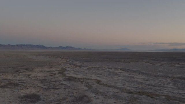 An Aerial shot of an vast desert and distant mountains at dusk near Sevier Lake, Utah, USA