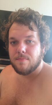 Young man with curly hair and beard looking