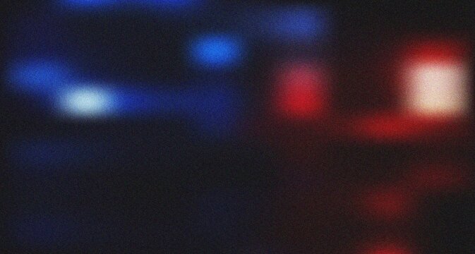 Intense abstract blue and red blurred light spots on a grainy dark surface evoking a city night