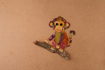 Monkey made from autumn leaves sitting on a branch. Flat lay craft photography. Autumn nature and children creativity concept. Design for poster, print, postcard. Flat lay with copy space © Elena