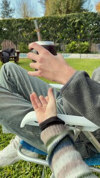 Close up of two hands sharing traditional yerba mate, Argentine drink in the garden a spring day. Latin Heritage, Uruguay Paraguay and Brazil typical social beverage
