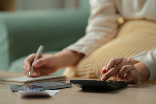 Title Personal budgeting concept. Anonymous person calculating household expenses with calculator while writing notes beside smartphone at home. Budget, finance, savings, planning, expenses