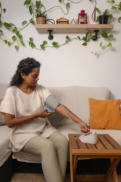 vertical young woman checking blood pressure at home