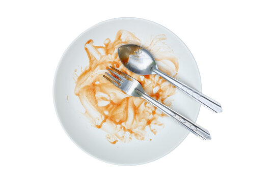 round white plate,fork and spoon stained with red sauce after finishing meal isolated on white.