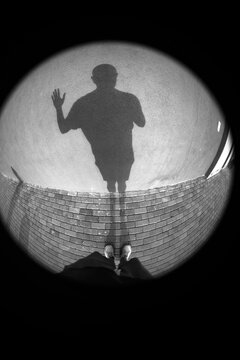 Circular fisheye POV silhouette shadow of man on wall with copy space