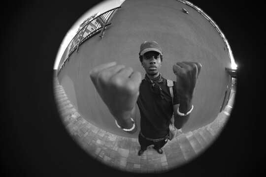 Circular fisheye black and white portrait of man showing fists with copy space