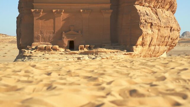 Lonely castle - largest tomb at Hegra archaeological site in Saudi Arabia Al Ula desert, camera moves up from sandy ground to reveal the large structure