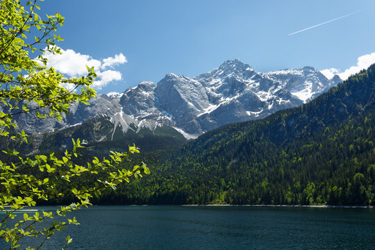 Travel landscape of Eibsee lake and Zugspitze mountain peak in Alps in Bavaria, Germany, scenic summer nature panorama with forest und mountains. Alpine landscape
