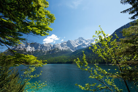 Travel landscape of Eibsee lake and Zugspitze mountain peak in Alps in Bavaria, Germany, scenic summer nature panorama with forest und mountains. Alpine landscape