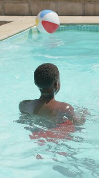 Vertical video: Drifting ball on edge making teen turning, reaching ball in red trunks at home pool