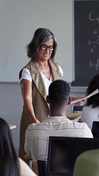 Teacher giving exam sheet to High School students. Preparation course for University