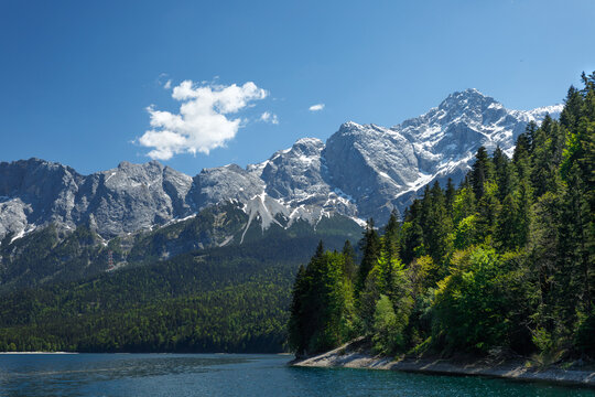 Travel landscape of Eibsee lake and Zugspitze mountain peak in Alps in Bavaria, Germany, scenic summer nature panorama with forest und mountains. Alpine landscape
