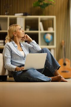 Woman Working in a Small Office Space While Sitting on the Floor With a Laptop
