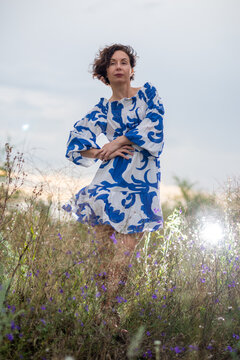 Woman in Blue Patterned Dress Standing in Wildflower Field