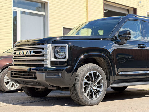 Black Haval H9 luxury off-road SUV wrapped in clear polyurethane anti-gravel film for paint protection, parked outdoors. Chinese premium 4x4 vehicle with glossy protective PPF wrap against chips. 