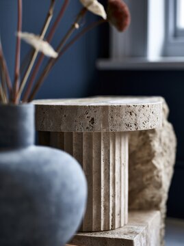 Modern travertine pedestal side table with ceramic vase in minimalist luxury interior