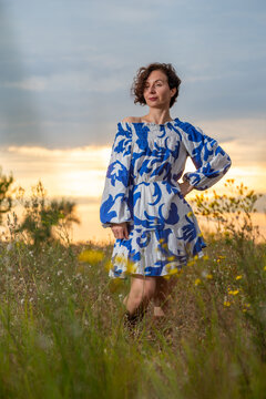 Woman in Blue Dress in Wildflower Field at Sunset