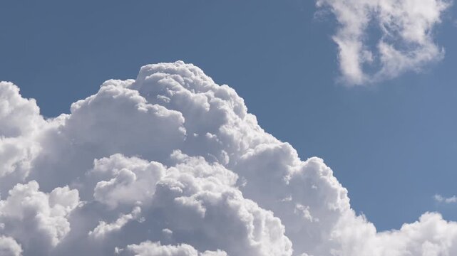 Timelapse video of large white cumulus clouds moving across a blue sky, showing natural weather patterns, atmospheric motion, peaceful landscape and changing conditions in the environment