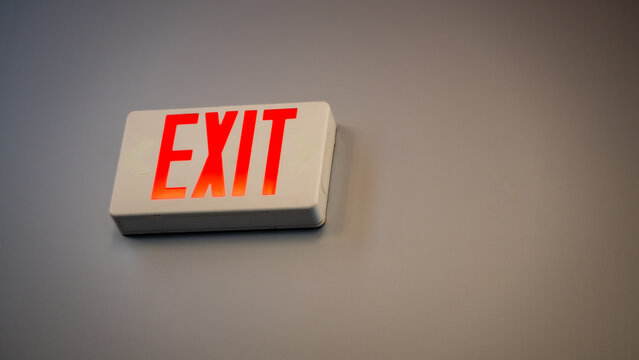 Closeup of Red LED Exit Sign on Interior Wall. safety, guidance, and emergency preparedness background banner