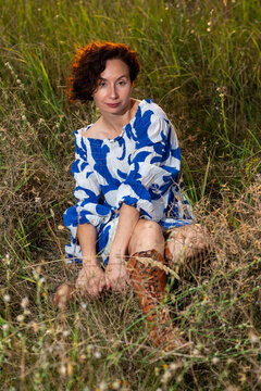 Woman in Blue Dress Sitting in Tall Grass