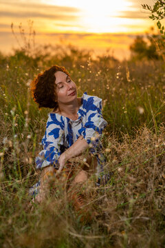 Woman Relaxing in Meadow at Sunset